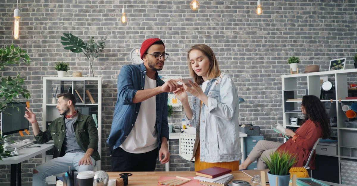 Jeunes professionnels collaborant dans un bureau moderne, partageant des idées et utilisant la technologie.