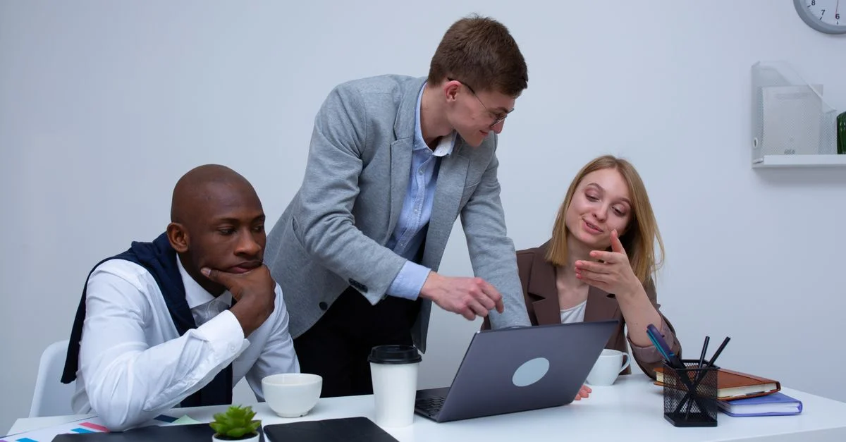 Une équipe diversifiée collaborant dans un environnement de bureau moderne, discutant du travail sur un ordinateur portable.