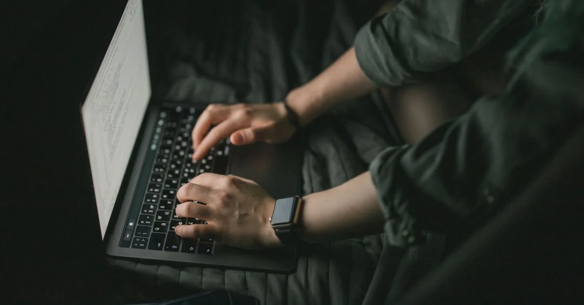 Des mains tapant sur un ordinateur portable dans un cadre sombre, concept de technologie et de concentration.