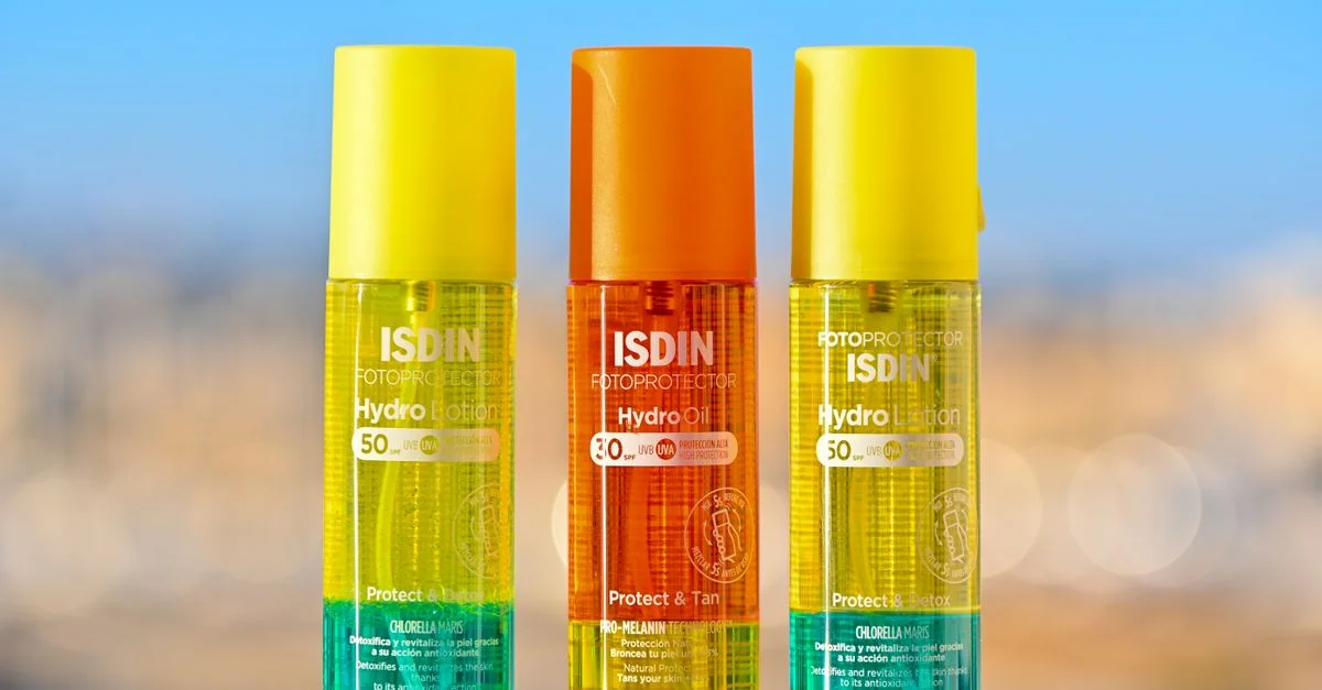 Trois flacons colorés de protection solaire ISDIN sur un fond flou, mettant en valeur des emballages vifs.