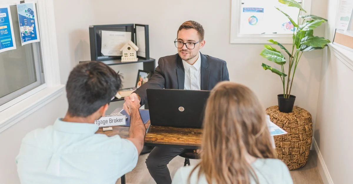 Hommes et femmes discutant d'hypothèque avec un courtier dans un cadre de bureau moderne.