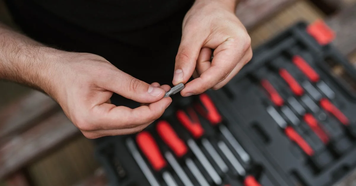 Gros plan sur des mains avec des outils dans un atelier, mettant l'accent sur la précision et l'habileté.