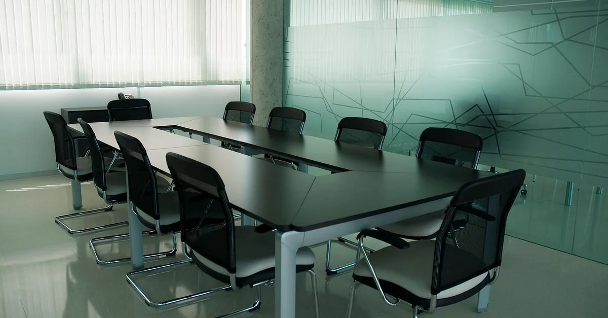 Salle de conférence élégante avec des chaises noires épurées et un design de mur en verre moderne.